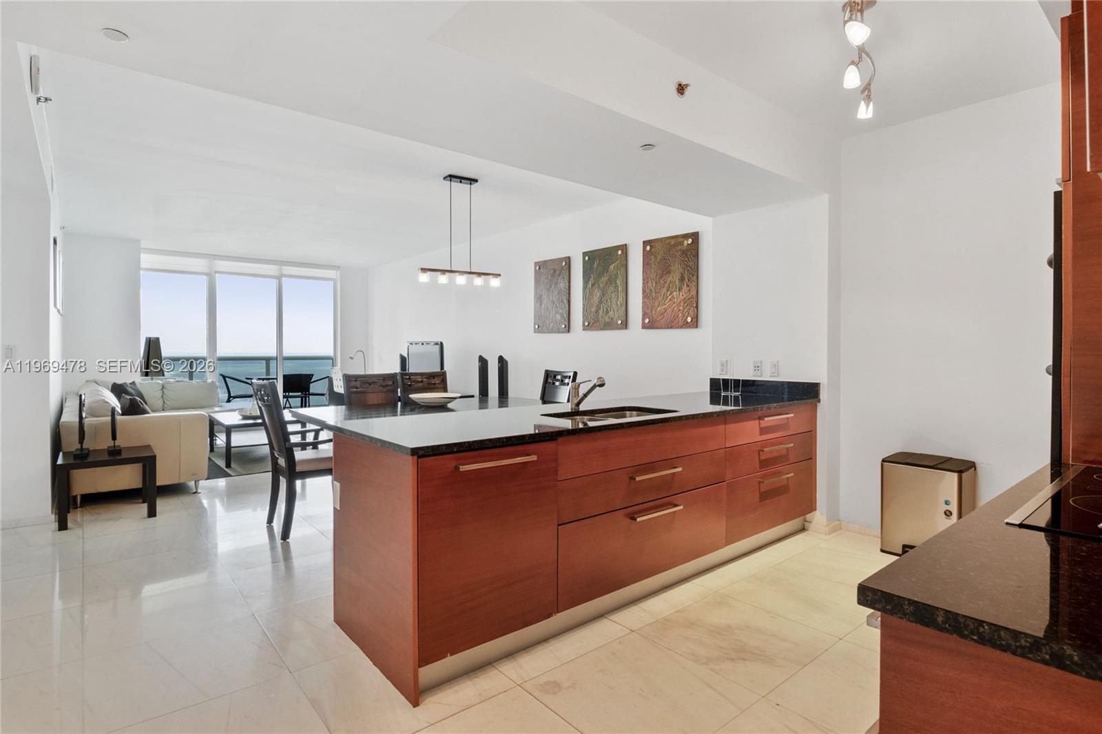 A kitchen island with dark countertops and wood cabinetry sits in an open-concept living space — 1830 S OCEAN DR # 3211, Hallandale Beach FL 33009, HALLANDALE BEACH, FL