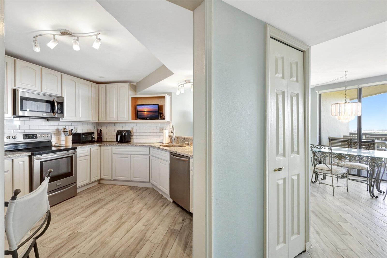 A kitchen with white cabinets and stainless steel appliances opens to a dining area — 9500 S Ocean Drive # 10, Jensen Beach FL 34957, JENSEN BEACH, FL