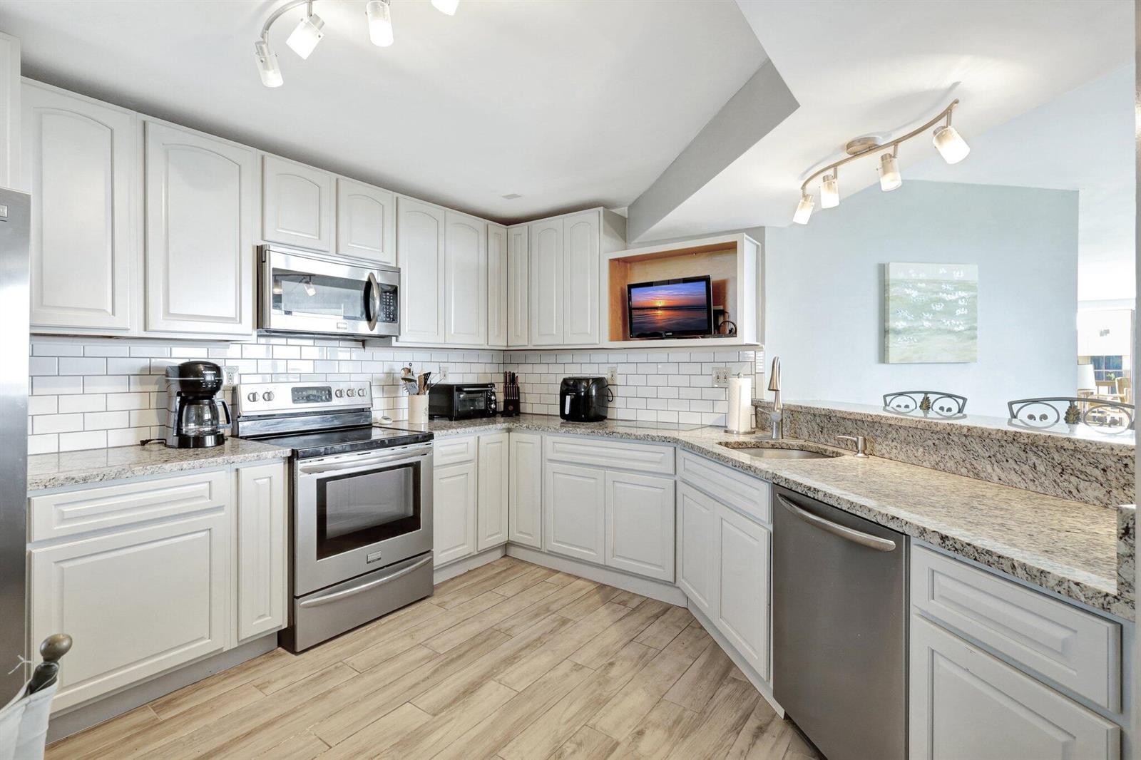 A kitchen with white cabinets, stainless steel appliances, granite countertops, and white subway tile backsplashes — 9500 S Ocean Drive # 10, Jensen Beach FL 34957, JENSEN BEACH, FL