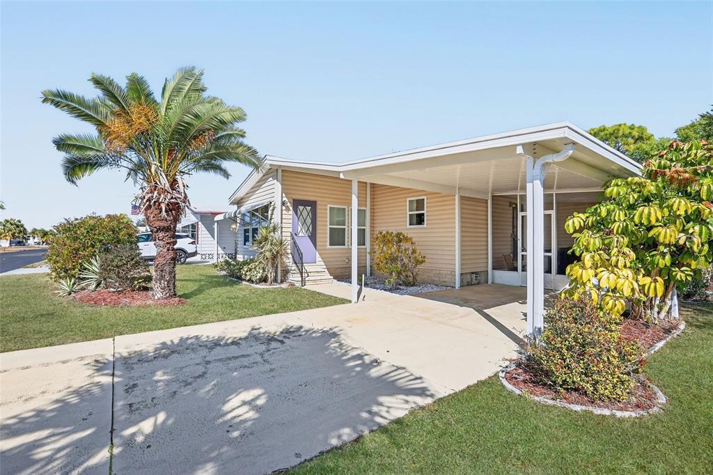 A single-story mobile home features light tan siding, a carport, and a palm tree — 855 IGLESIA DRIVE, NORTH PORT, FL