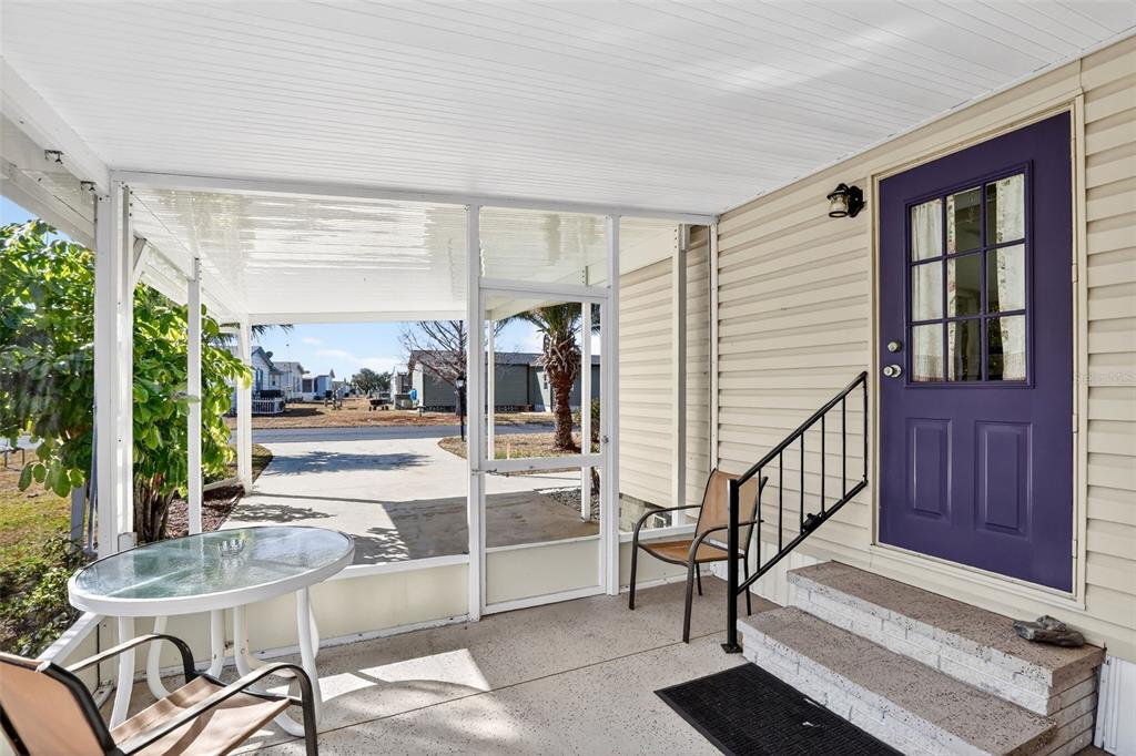 A screened-in porch features a purple front door, concrete steps, and a small bistro table — 855 IGLESIA DRIVE, NORTH PORT, FL