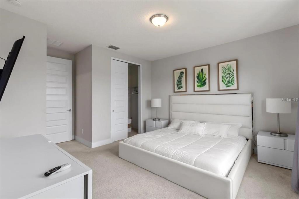 A bedroom features a white upholstered bed, two nightstands, and three framed botanical prints — 832 DRIVING RANGE COURT, KISSIMMEE, FL