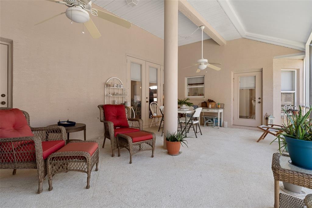 A covered outdoor patio features wicker furniture, ceiling fans, and a central support column — 382 ROYAL PALM WAY, SPRING HILL, FL