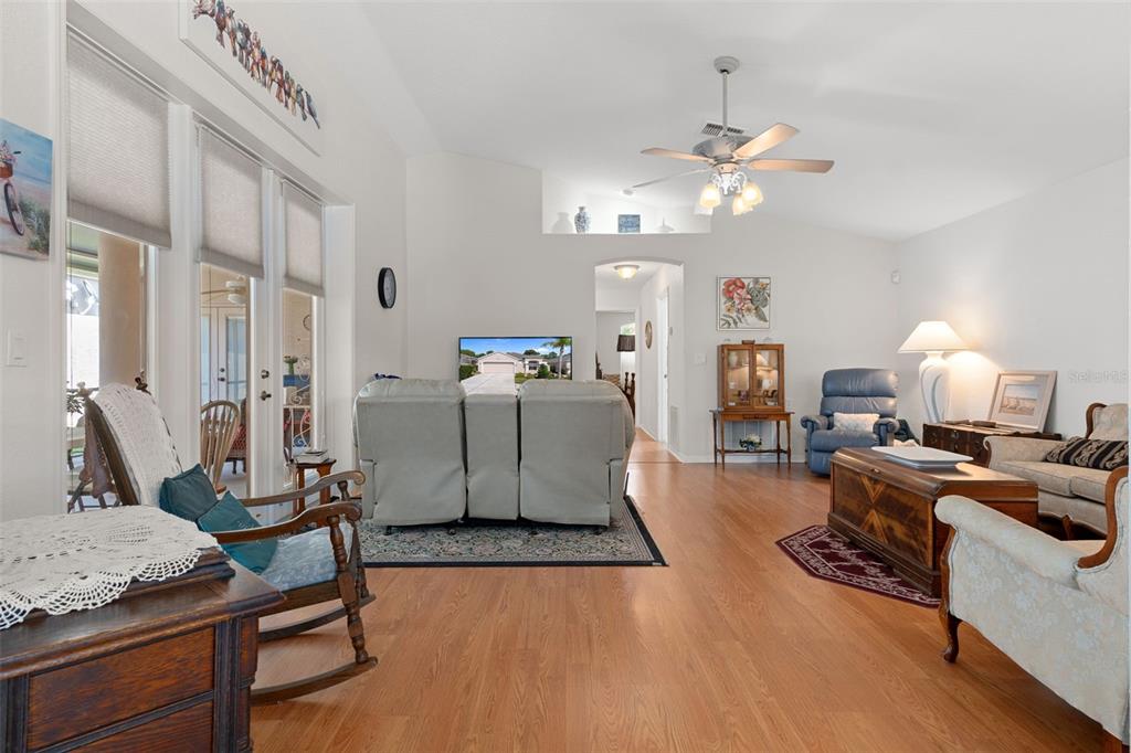 A living room features light wood flooring, a vaulted ceiling, and a ceiling fan — 382 ROYAL PALM WAY, SPRING HILL, FL