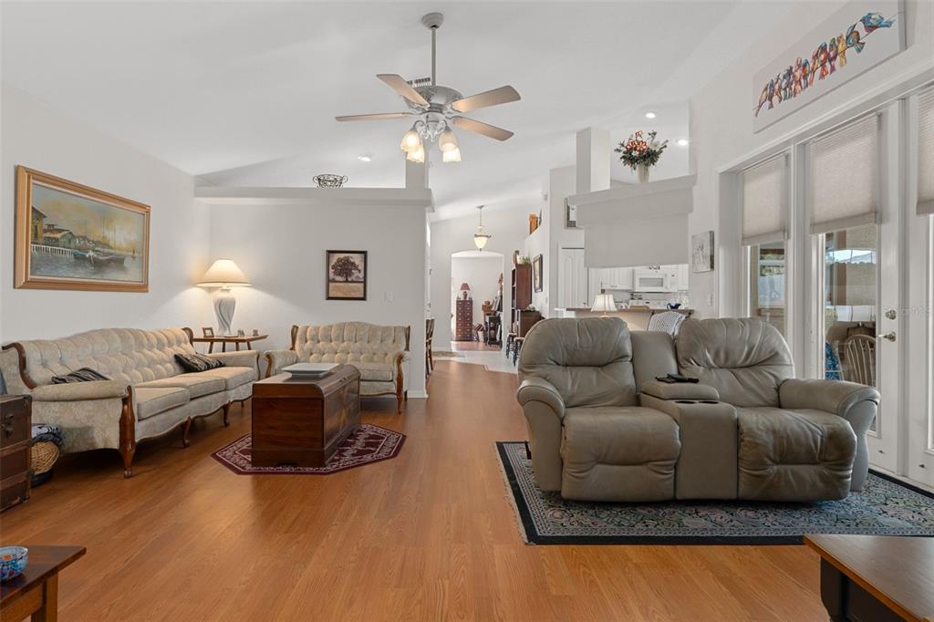 A living room features light wood flooring, a ceiling fan, and two separate seating areas — 382 ROYAL PALM WAY, SPRING HILL, FL