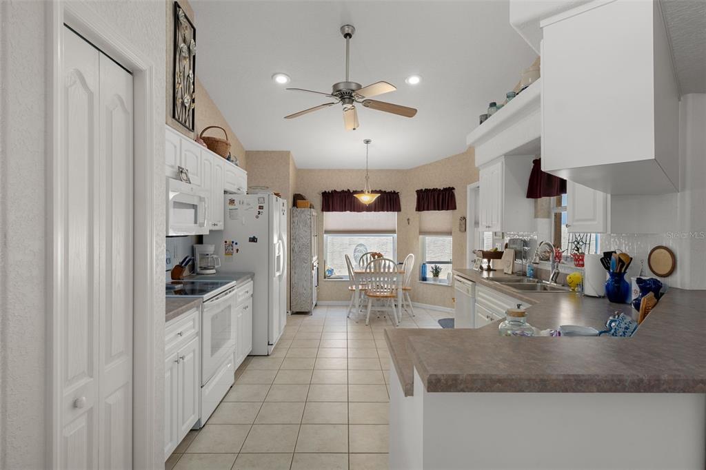 A kitchen with white cabinets, tile flooring, and a dining area with a breakfast table — 382 ROYAL PALM WAY, SPRING HILL, FL