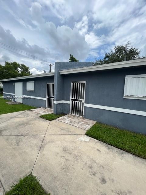 A gray single-story house exterior features white security bars on the doors and windows — 2249 NW 66th St # 2249, Miami FL 33147, MIAMI, FL