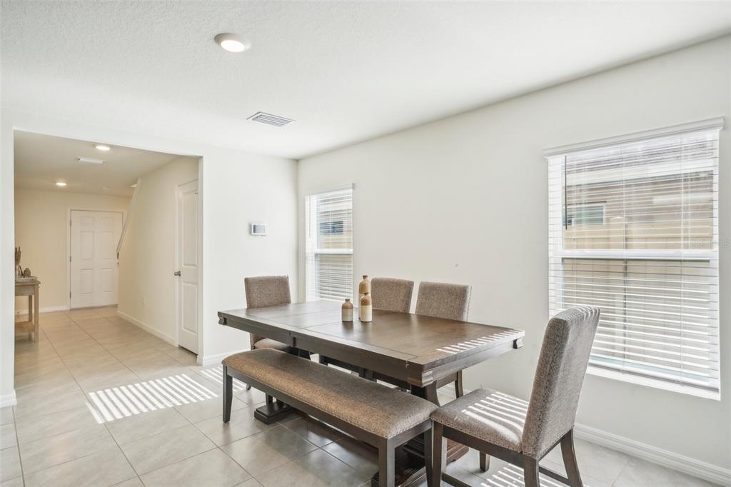 A dining room features a wooden table with a bench and chairs on tiled floors — 11637 SAW PALMETTO LANE, RIVERVIEW, FL
