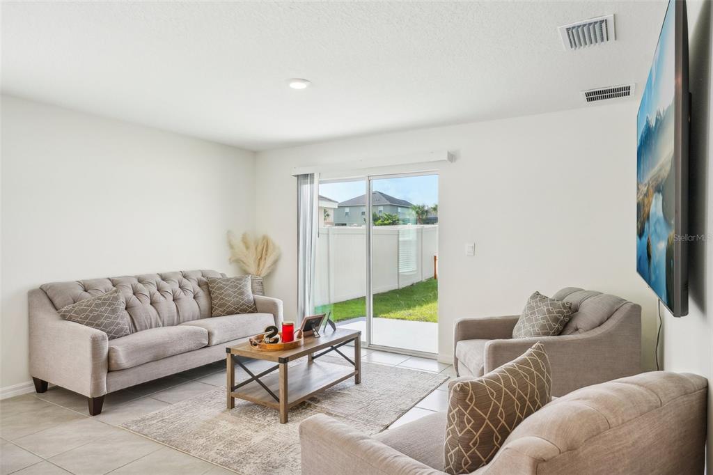 A living room features a tufted sofa, two armchairs, a coffee table, and sliding glass doors — 11637 SAW PALMETTO LANE, RIVERVIEW, FL