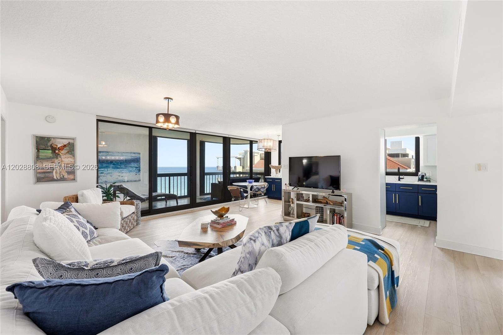 A bright living room features a white sectional sofa, ocean views, and an adjacent kitchen — 5380 N Ocean Dr # 18B, Singer Island FL 33404, SINGER ISLAND, FL