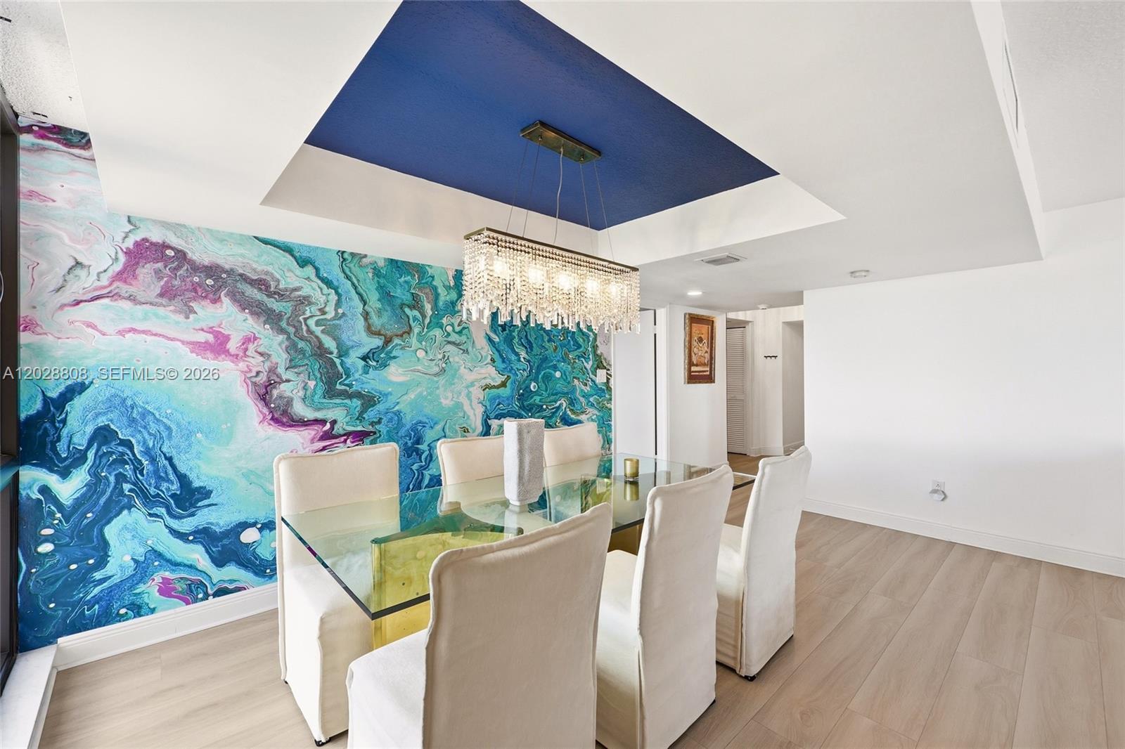 A dining room features a glass table, white chairs, and a vibrant blue marble-patterned wall — 5380 N Ocean Dr # 18B, Singer Island FL 33404, SINGER ISLAND, FL