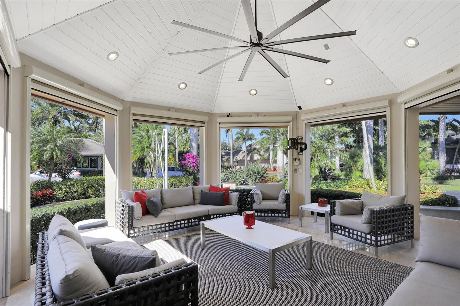 A sunroom with a large ceiling fan, wicker furniture, and views of a landscaped yard — 431 S Cortez Drive # 431, Margate FL 33068, MARGATE, FL