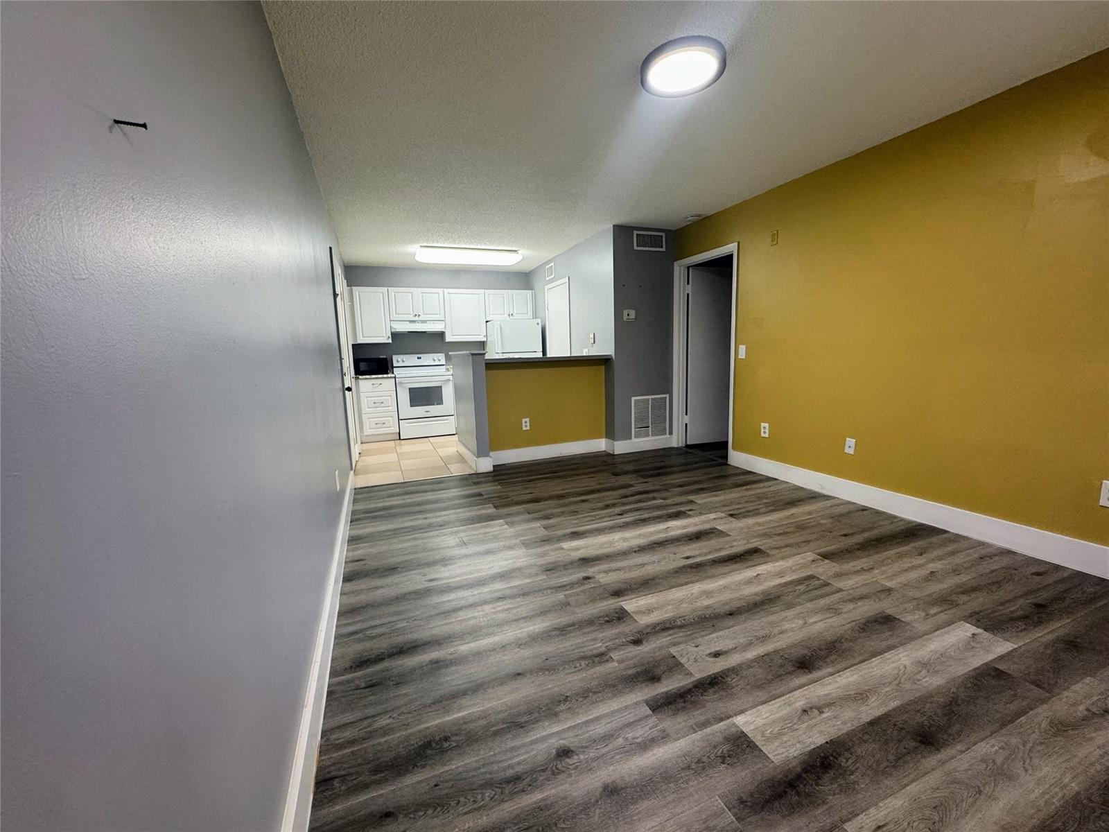 An open-concept living area features gray walls, a mustard accent wall, and wood-look flooring — 4361 W Mcnab Road # 17, Pompano Beach FL 33069, POMPANO BEACH, FL