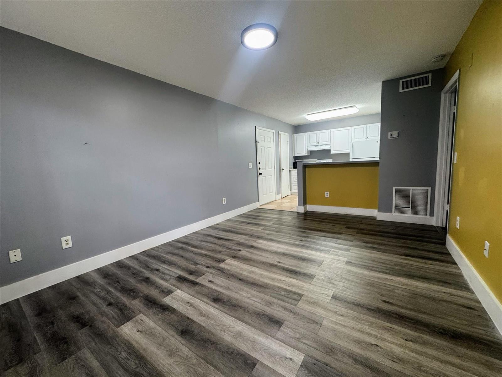 An open-concept living area features gray walls, a yellow accent wall, and wood-look flooring — 4361 W Mcnab Road # 17, Pompano Beach FL 33069, POMPANO BEACH, FL