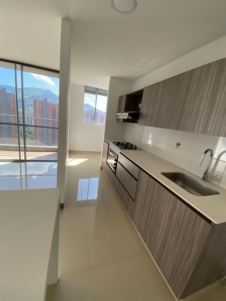 A modern kitchen features wood-grain cabinets, light countertops, and a balcony with mountain views — 53-90 Calle 75 AA Sur # 2601, FL 055413, FL
