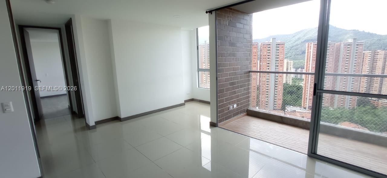 An empty room with white tile floors, a brick accent wall, and a balcony overlooking buildings — 53-90 Calle 75 AA Sur # 2601, FL 055413, FL