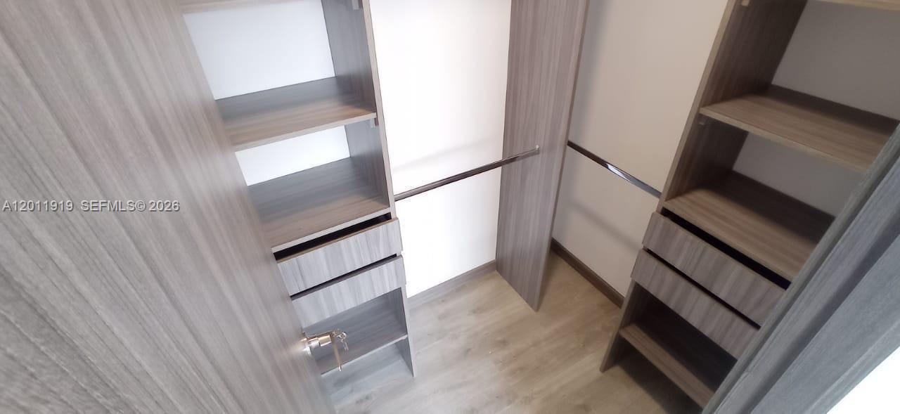 A walk-in closet features wood-grain shelving, drawers, and a hanging rod — 53-90 Calle 75 AA Sur # 2601, FL 055413, FL
