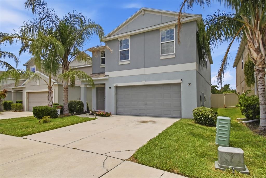 A two-story house with a gray exterior, a two-car garage, and palm trees in front — 17032 YELLOW PINE STREET, WIMAUMA, FL