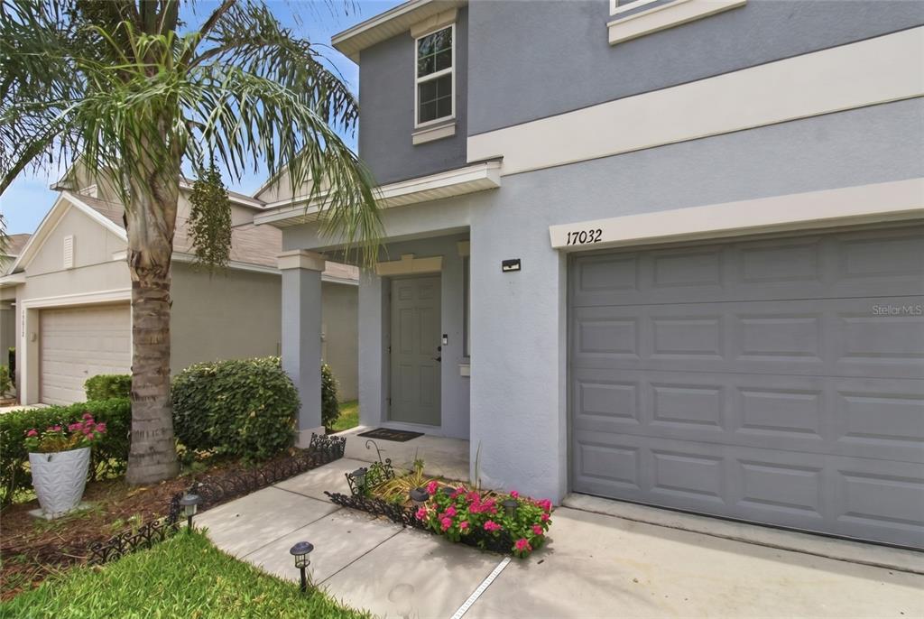 A two-story house exterior features a gray garage, a covered entryway, and a palm tree — 17032 YELLOW PINE STREET, WIMAUMA, FL