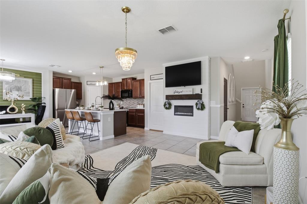 An open-concept living room and kitchen featuring a fireplace, television, and green accent decor — 17032 YELLOW PINE STREET, WIMAUMA, FL
