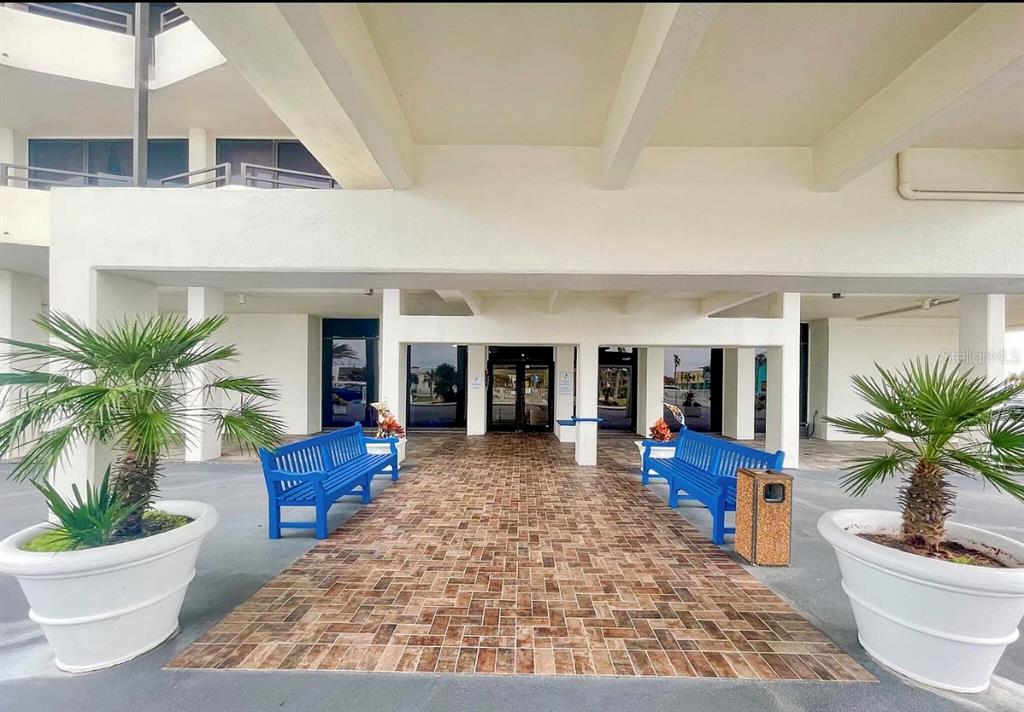 A covered outdoor entrance features a brick walkway, two blue benches, and potted palm trees — 2900 N ATLANTIC AVENUE UNIT 1503, DAYTONA BEACH, FL