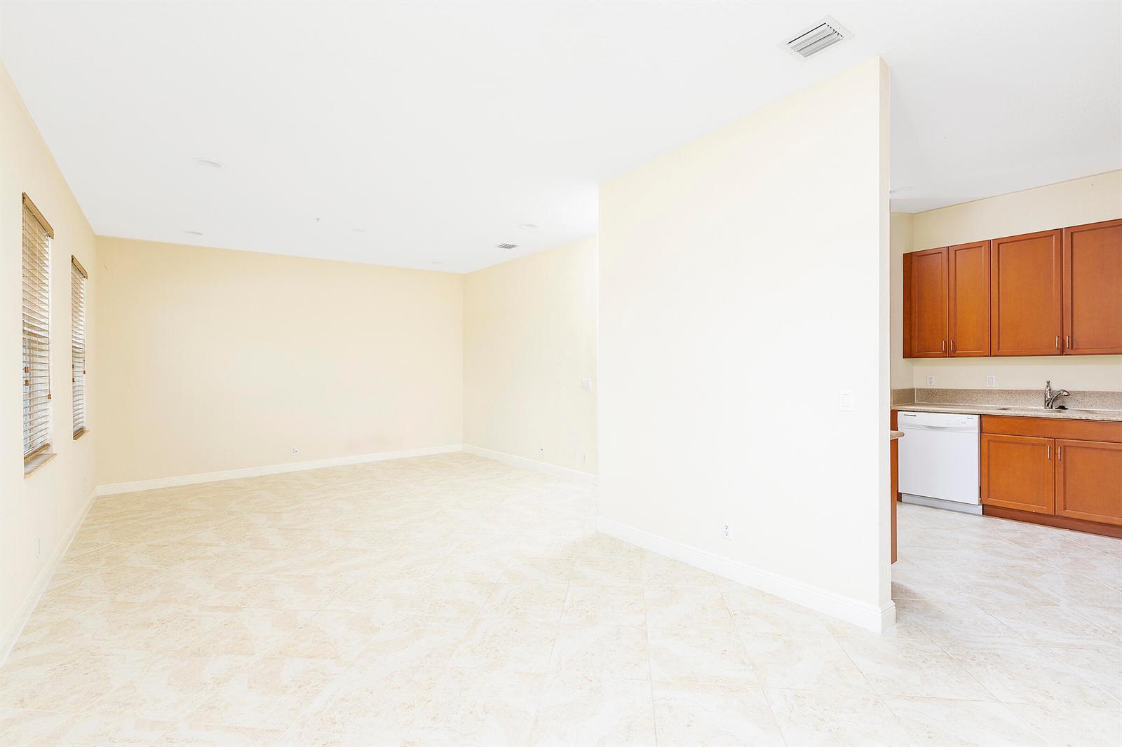 An open living area with tile floors leads to a kitchen with wood cabinets — 6807 Lakeside Circle N # 1, Davie FL 33314, DAVIE, FL