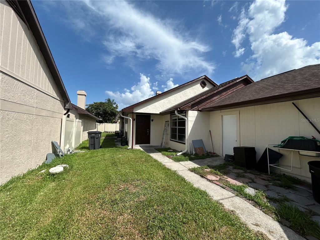 A side yard with a concrete walkway leads to a house entrance and a storage door — 7029 DRURY STREET, TAMPA, FL