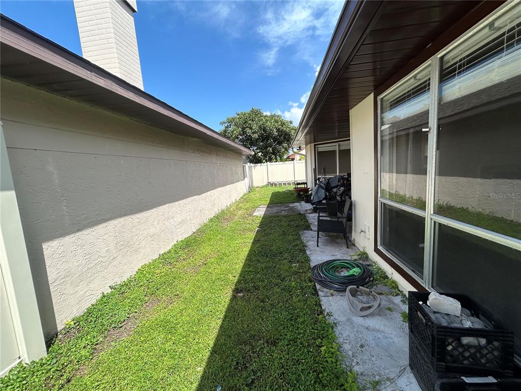 A narrow grassy side yard sits between two exterior walls of a house — 7029 DRURY STREET, TAMPA, FL