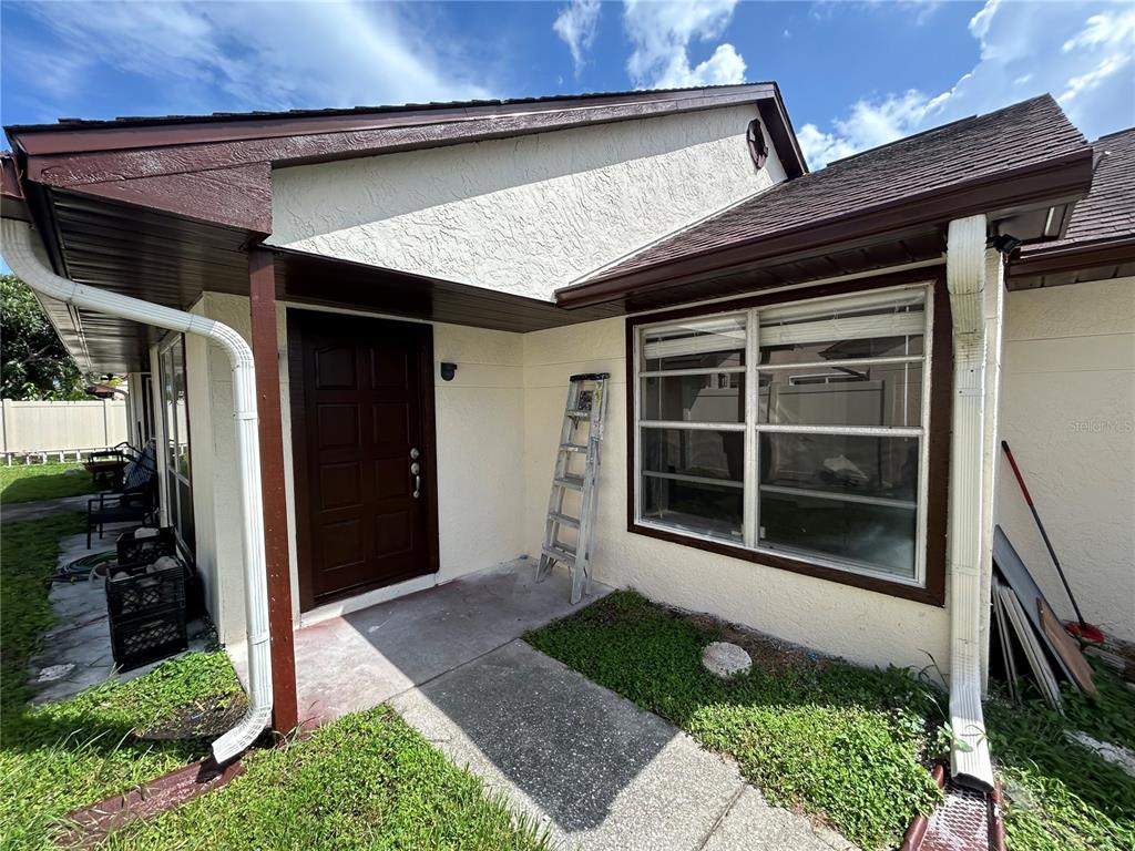 The exterior of a house features a brown front door, a window, and a metal ladder — 7029 DRURY STREET, TAMPA, FL