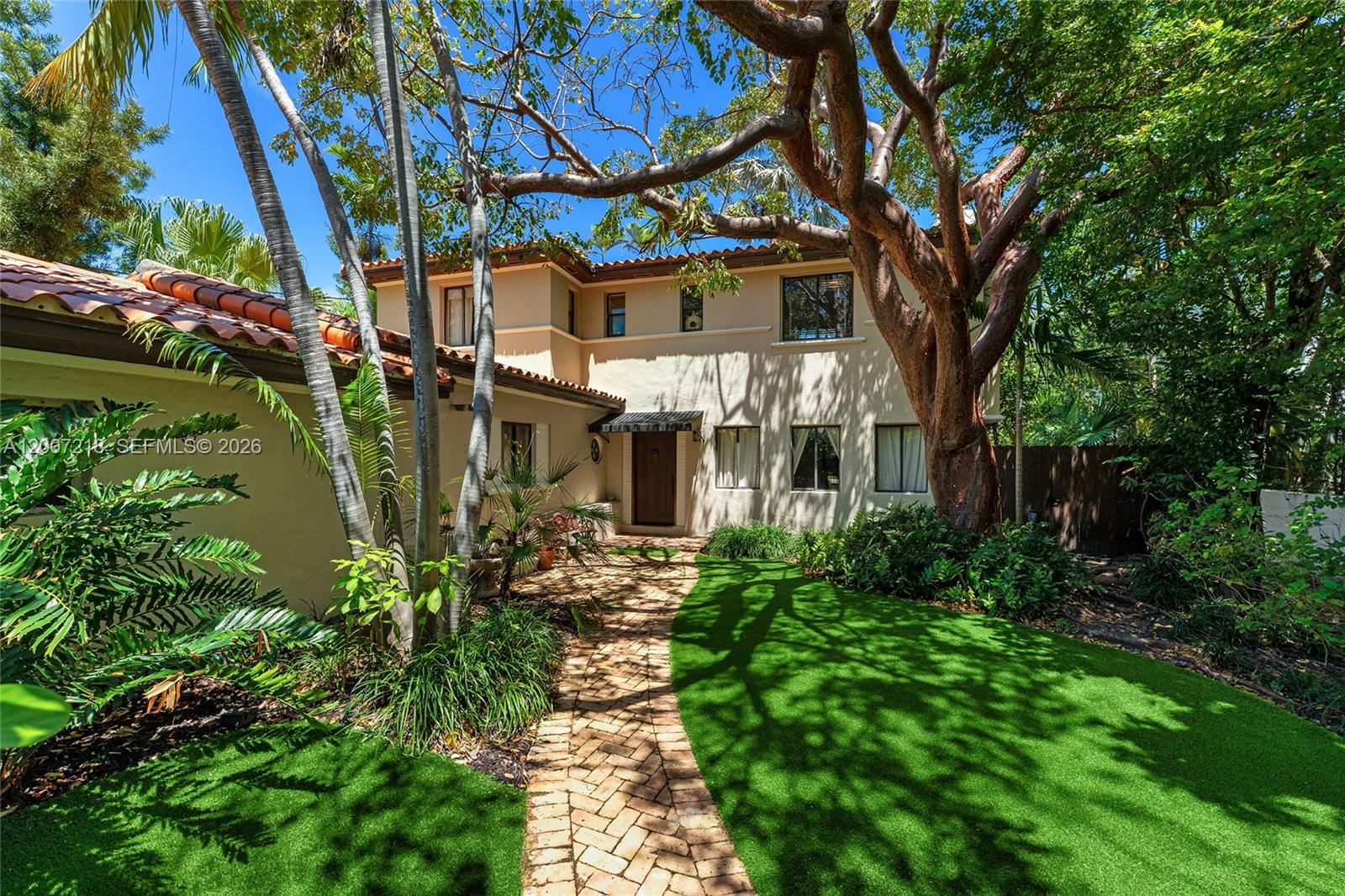 A two-story stucco house with a tile roof, brick walkway, and large trees — 6121 La Gorce Dr, Miami Beach FL 33140, MIAMI BEACH, FL