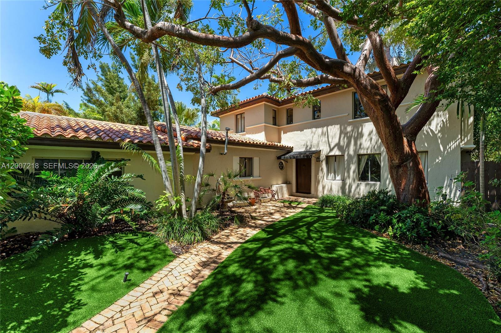 A two-story stucco house with a tile roof features a brick walkway and artificial turf — 6121 La Gorce Dr, Miami Beach FL 33140, MIAMI BEACH, FL