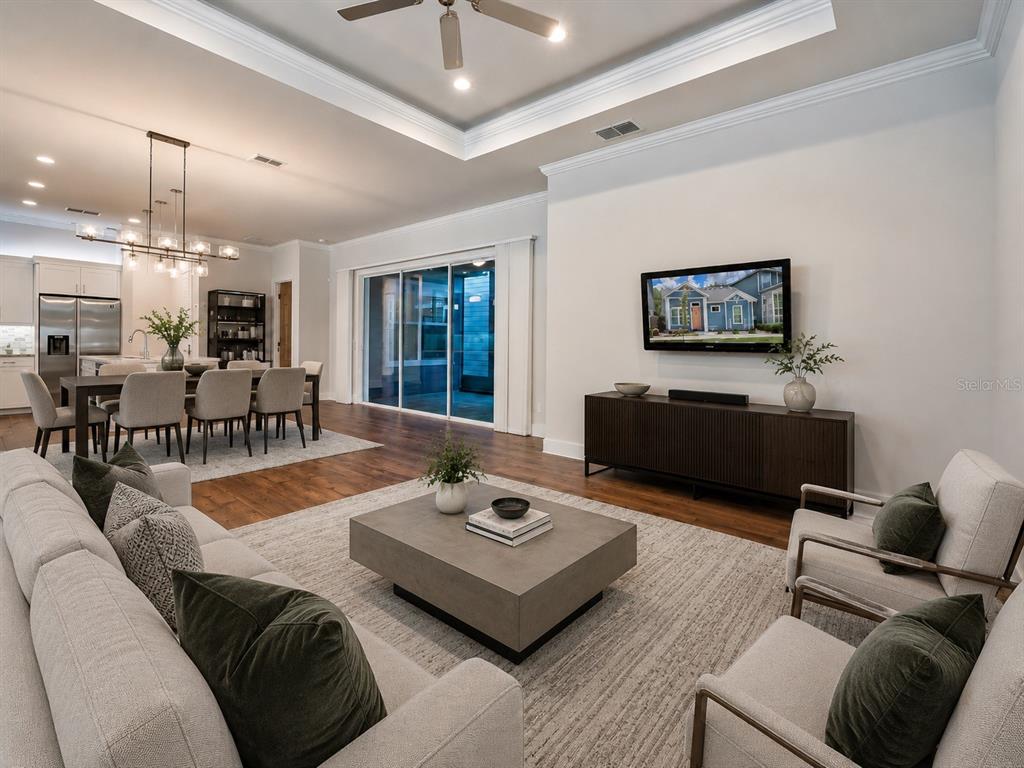 A modern open-concept living room features a tray ceiling, hardwood floors, and a dining area — 6463 SW 77TH DRIVE, GAINESVILLE, FL