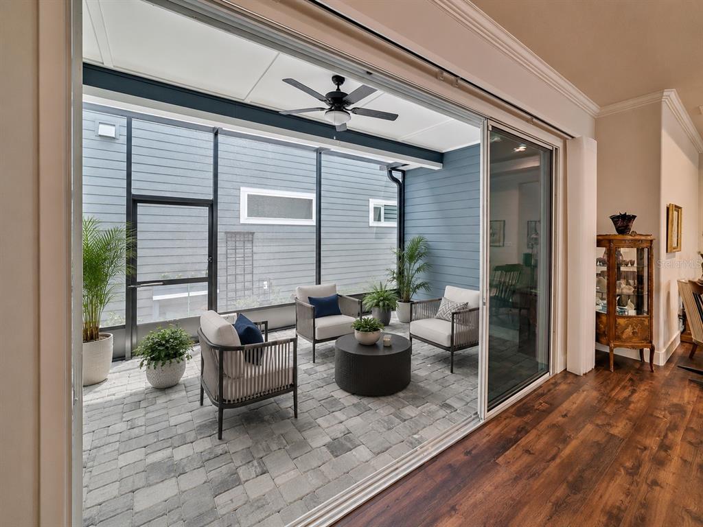 A covered patio with stone pavers, outdoor furniture, and a ceiling fan overlooks a yard — 6463 SW 77TH DRIVE, GAINESVILLE, FL