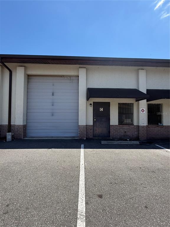 An exterior view of a commercial building unit featuring a roll-up door and entrance door — 3892 NE 40TH PLACE UNIT C, OCALA, FL