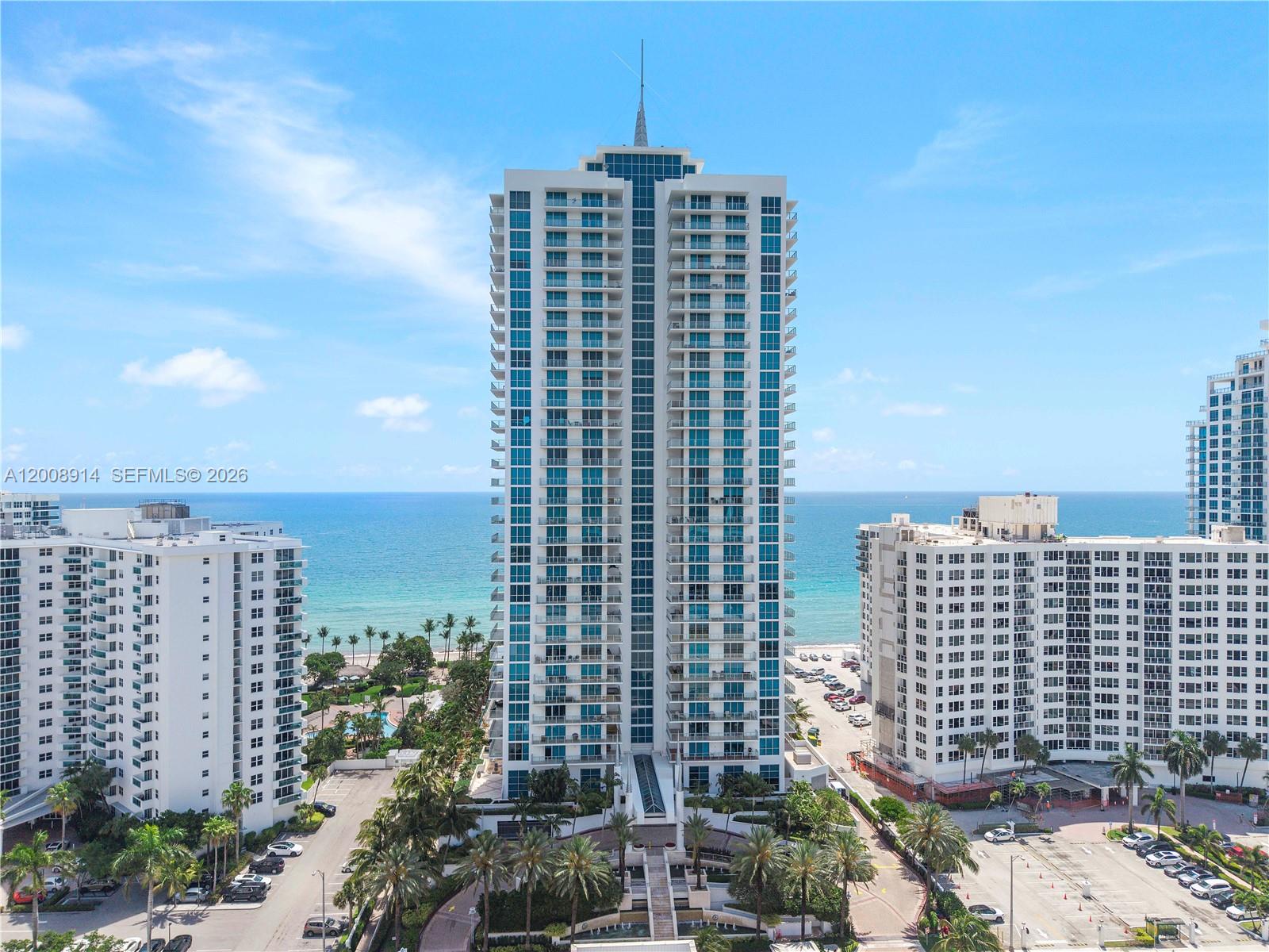 An aerial view shows a tall residential skyscraper situated between two shorter buildings near the ocean — 3101 S Ocean Dr # 2705, Hollywood FL 33019, HOLLYWOOD, FL