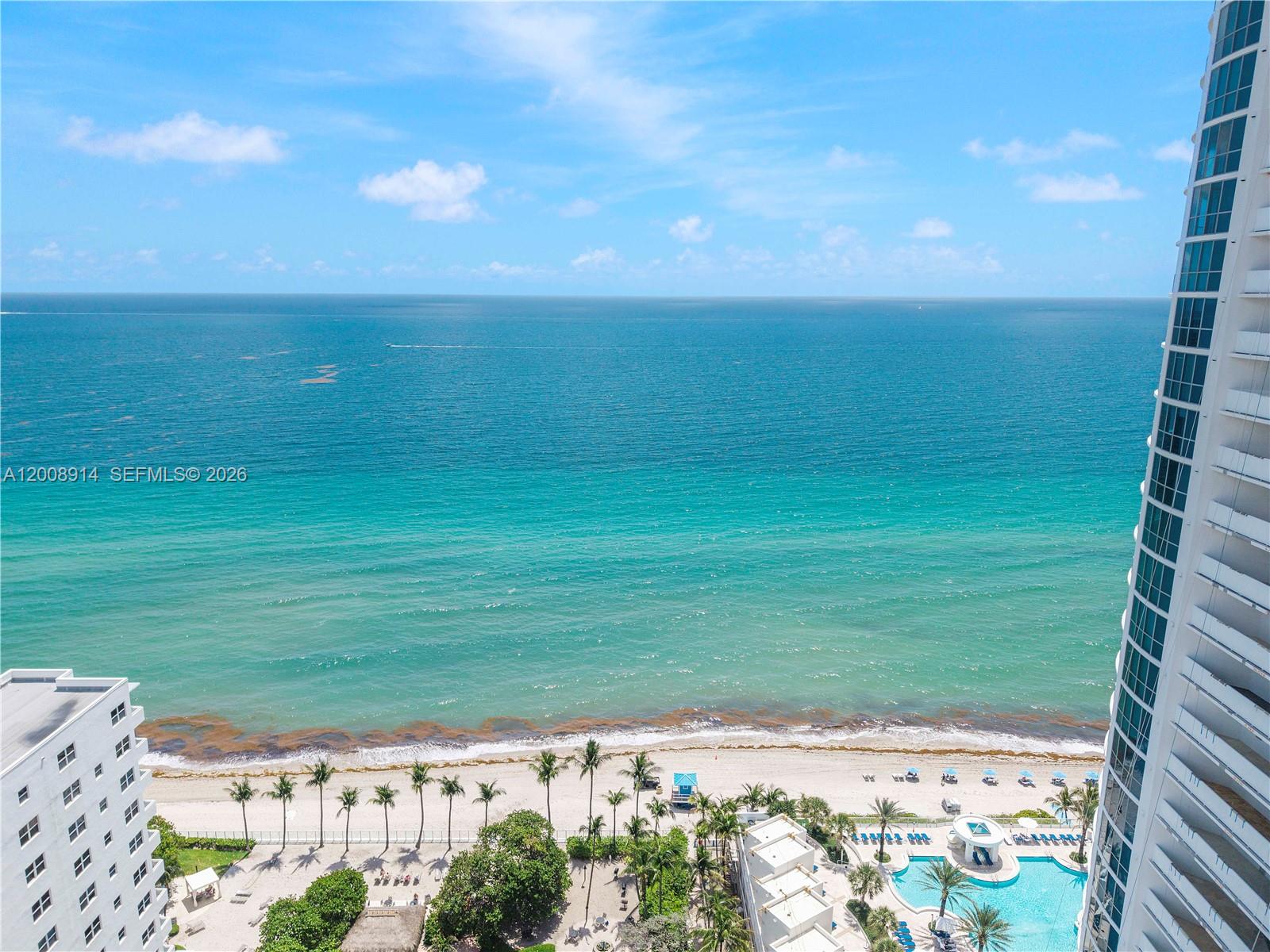 An elevated view shows a sandy beach, palm trees, a swimming pool, and the ocean — 3101 S Ocean Dr # 2705, Hollywood FL 33019, HOLLYWOOD, FL