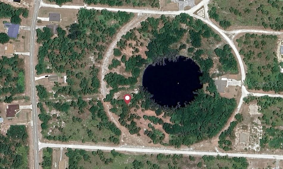 This aerial map shows a circular road surrounding a dark, circular sinkhole or pond — 12516 FIESTA CIRCLE, PUNTA GORDA, FL