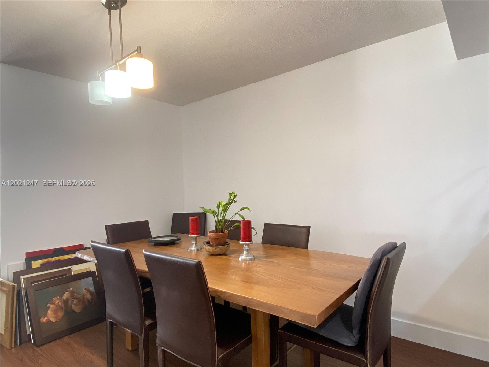 A dining room features a wooden table, six dark chairs, and a modern pendant light — 5757 Collins Ave # 703, Miami Beach FL 33140, MIAMI BEACH, FL