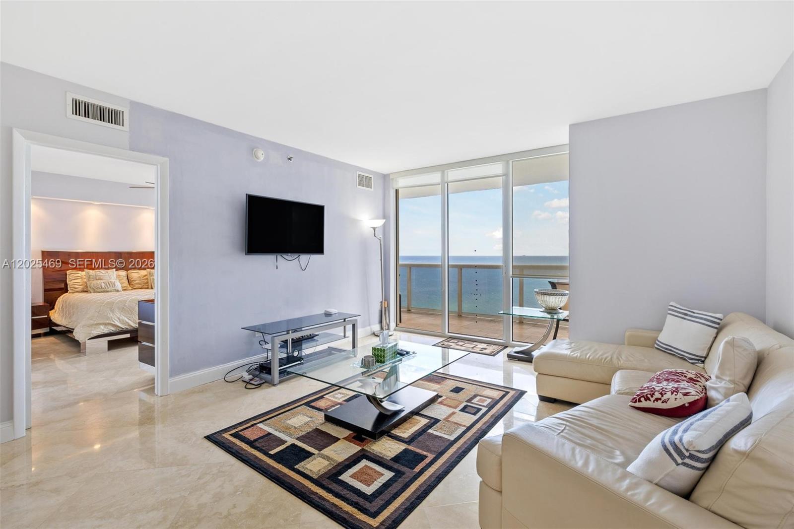 A living room features a white sofa, glass coffee table, and a balcony overlooking the ocean — 1830 S Ocean Dr # 2804, Hallandale Beach FL 33009, HALLANDALE BEACH, FL