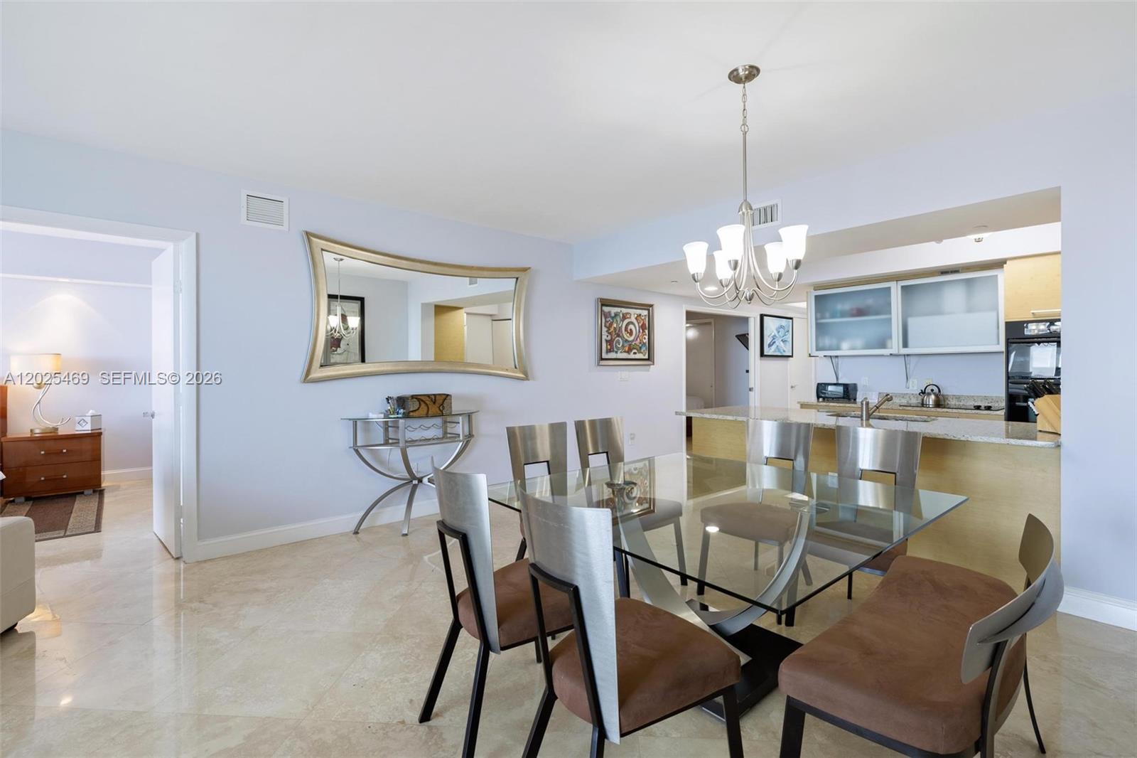 A dining area features a glass table, metal chairs, a wall mirror, and an open kitchen — 1830 S Ocean Dr # 2804, Hallandale Beach FL 33009, HALLANDALE BEACH, FL