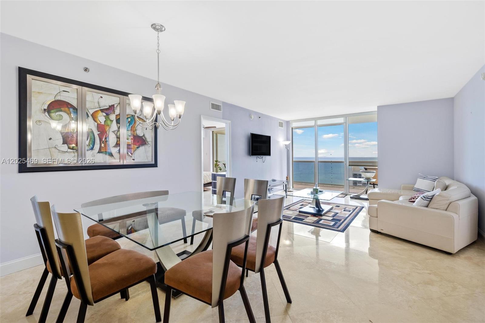 A dining and living area features a glass table, modern chairs, and ocean views — 1830 S Ocean Dr # 2804, Hallandale Beach FL 33009, HALLANDALE BEACH, FL