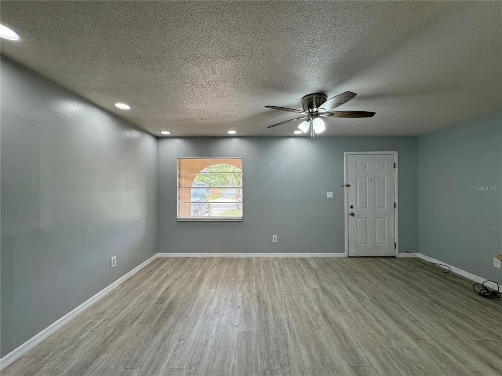 An empty living room features light gray walls, wood-look flooring, a ceiling fan, and a window — 775 HILLVIEW DRIVE, ALTAMONTE SPRINGS, FL