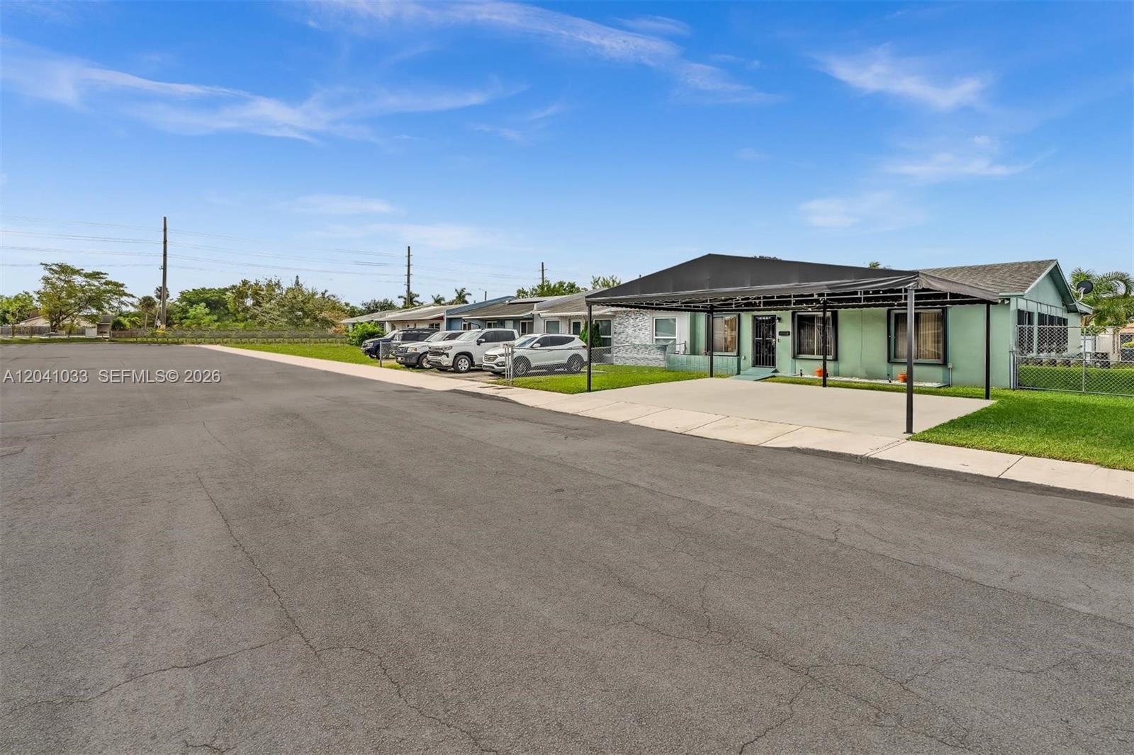 A light green house with a black metal carport sits along a paved street — 15012 SW 113th Ct, Miami FL 33176, MIAMI, FL