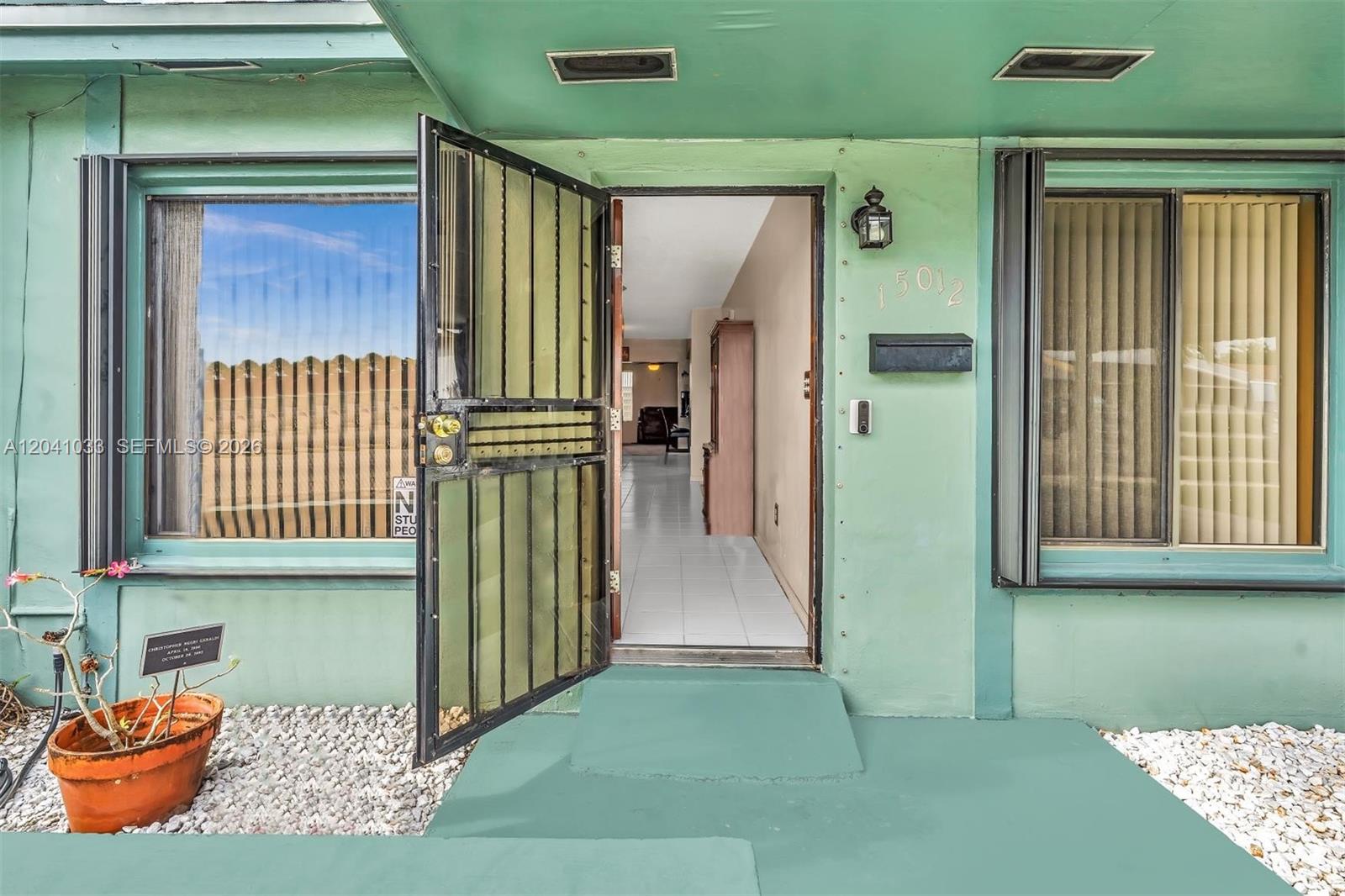 The exterior of a house features a green facade, a security door, and a front entrance — 15012 SW 113th Ct, Miami FL 33176, MIAMI, FL