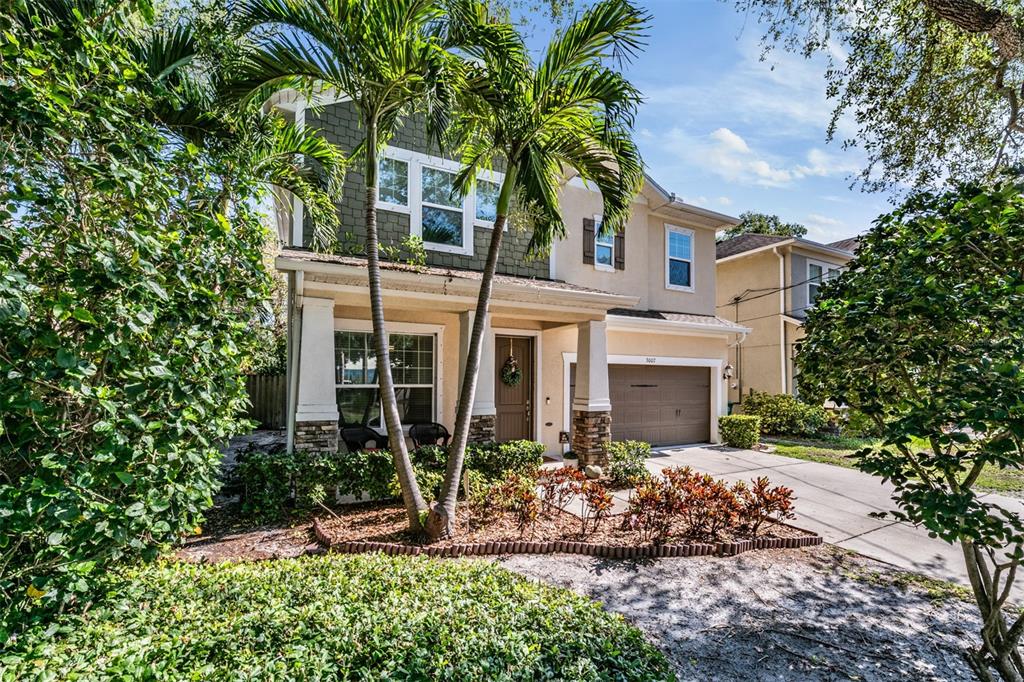A two-story house with a tan exterior, a brown garage door, and palm trees out front — 3007 W PALMIRA AVENUE, TAMPA, FL