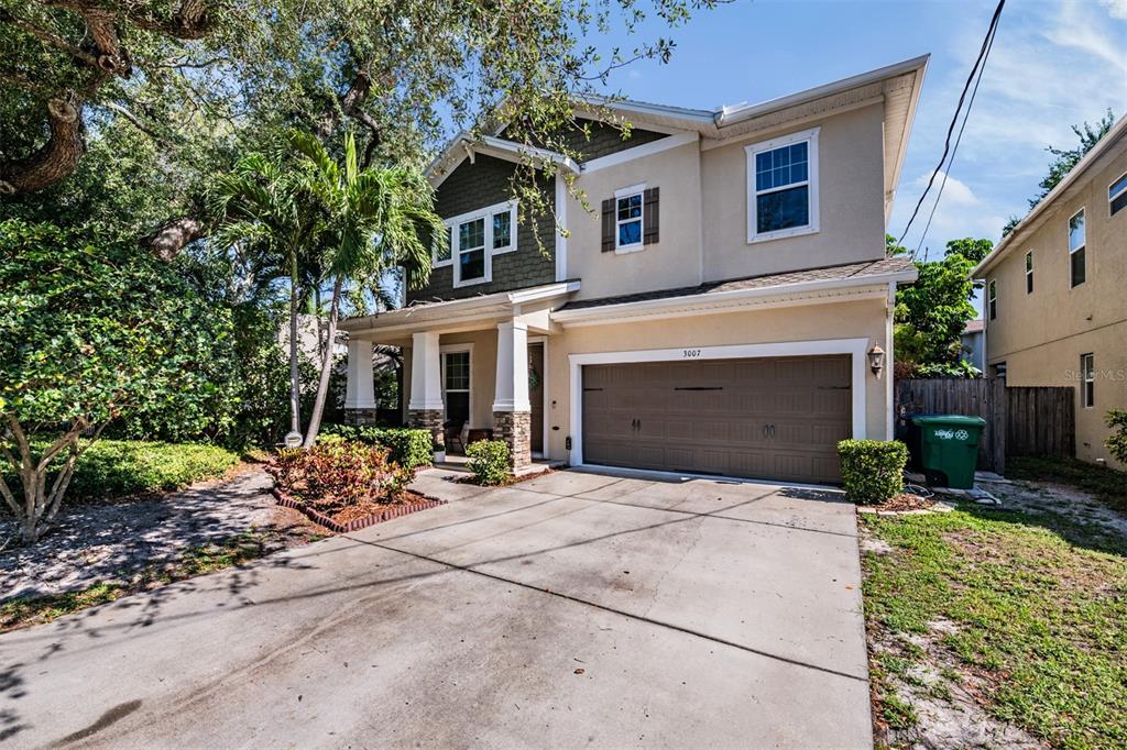 A two-story house with a beige stucco exterior, brown garage door, and a concrete driveway — 3007 W PALMIRA AVENUE, TAMPA, FL