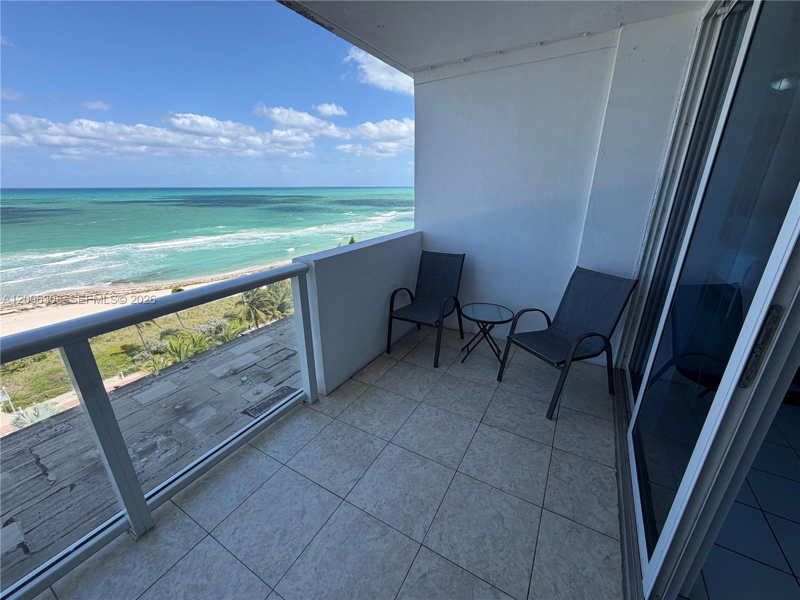 A balcony with tile flooring, two chairs, a small table, and an ocean view — MIAMI BEACH, FL