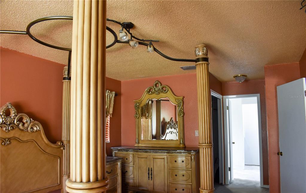 A bedroom features orange walls, a wooden canopy bed frame, and a matching ornate dresser — 6336 WOODEN STREET, NEW PORT RICHEY, FL