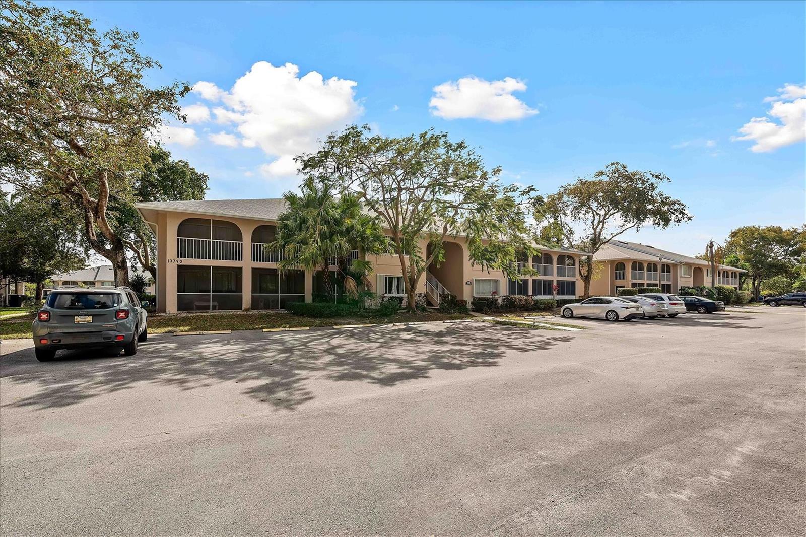 A multi-story apartment building with screened balconies sits behind a large paved parking lot — 13790 Oneida Drive # B1, Delray Beach FL 33446, DELRAY BEACH, FL