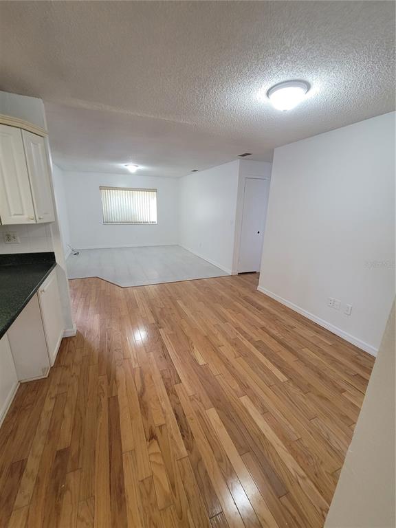 A kitchen with wood flooring opens into a living area with tile flooring and windows — 4825 SQUIRES DRIVE, TITUSVILLE, FL